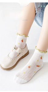 Detail of breathable mesh baby socks with carrot patterns and green ruffle trim