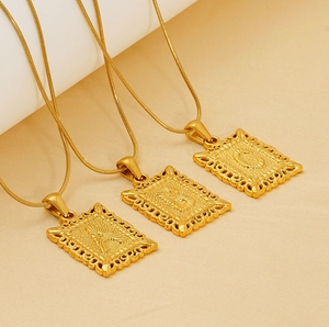 Three gold vintage rectangle pendant necklaces with snake chains on beige fabric
