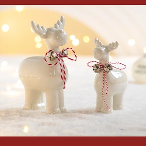 Close-up of ceramic Christmas reindeer figurines with red bells and cotton ropes