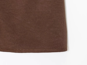 Detail of dark brown twill fabric with precise pleats and high-quality textured stitching