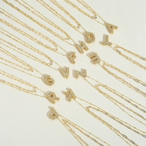 Gold layered necklace with zircon-encrusted initial pendants on bead and paperclip chains