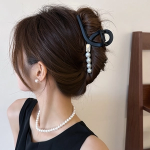 Pince à cheveux noire mate élégante avec perles portée par un modèle, style minimaliste