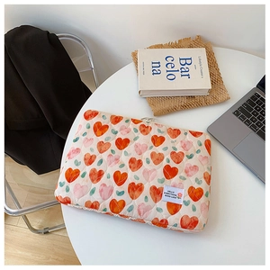 Quilted laptop sleeve with red hearts and green leaves on a white lifestyle table
