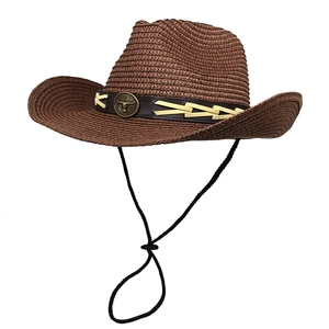 Detail of western straw cowboy hat featuring vintage bull head metal emblem and leather band