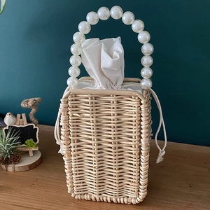 Detail of handmade woven rattan bag with pearl handle and beige drawstring lining cloth
