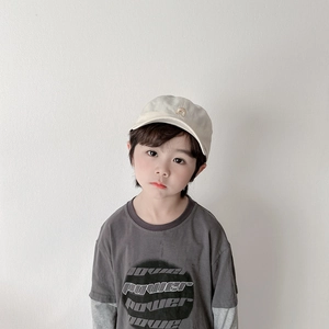 Détail d'une casquette beige pour enfant avec broderie ours et t-shirt décontracté