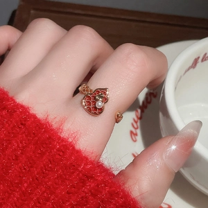 Macro shot of 18k gold plated open ring with red heart-shaped enamel and white pearl detail
