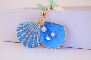 Detail of blue shell keychain with rhinestones, gold plating and pearl pendant