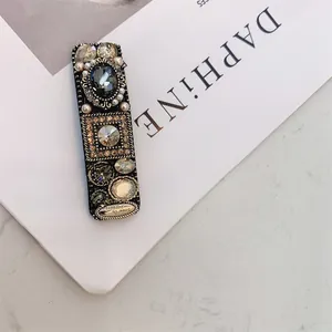 Detail of vintage hair clip with grey stones, pearls and 'Love is Forever' metal tag