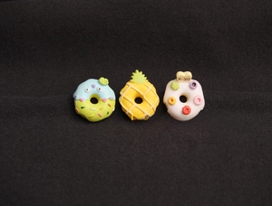 Detailed close-up of three colorful resin cartoon donut charms for DIY craft and accessory