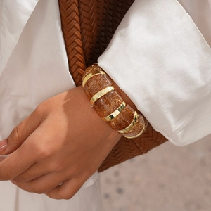 Close-up of golden amber acrylic bracelet with glitter insets and metallic link rings