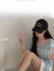 Detail of a light blue knit top paired with white polka dot shorts and a black baseball cap