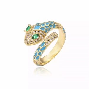 Gold snake ring with blue enamel scales and white zircon accents in a wrap-around style