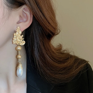 Close-up of vintage gold floral earrings with large teardrop pearls on a female model