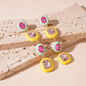 Close-up of geometric long earrings with mint green and yellow enamel on stone stand