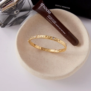 Close-up of gold 18K plated stainless steel bangle with hammered texture and CZ stones
