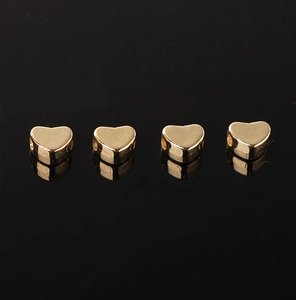 Macro-opname van vier gouden hartvormige metalen kralen voor DIY-sieradenprojecten