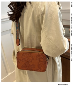 Detail of vintage brown PU leather bag with floral embossing and ethnic wide strap