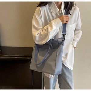Blue nylon tote bag with adjustable strap shown on model during daily commute