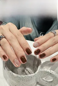 Detail of dark coffee cat-eye press-on nails with silver glitter and square shape