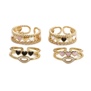 Detail of four gold adjustable heart rings with pink, black, and white enamel accents