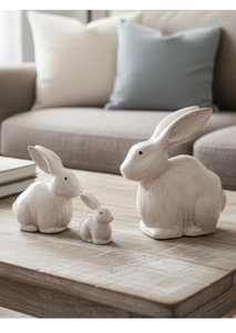 Dettaglio di tre statuine di coniglio minimaliste in legno con texture su un tavolo di legno