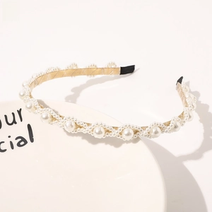 Detail of elegant gold metal headband featuring wavy imitation pearl inlay and black tips
