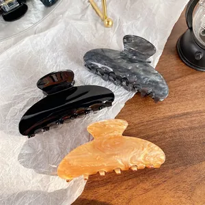 Three-piece set of large acrylic shark hair clips in black, marble, and amber patterns