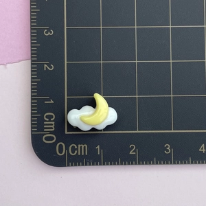 Close-up of yellow resin moon and white cloud charm showing 1cm size detail