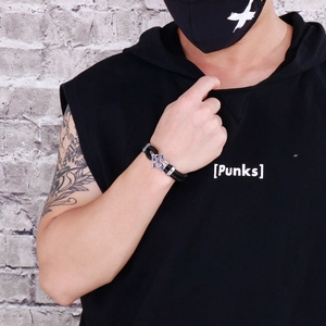 Detail of a men's punk black braided leather bracelet with a silver cross on wrist