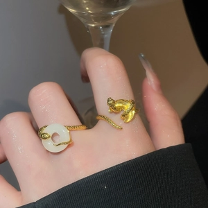 Close-up of elegant gold leopard and jade-style open rings worn on female fingers