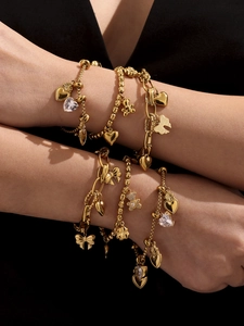 Detail of 18k gold plated bear and heart charms on multi-layered stainless steel bracelets