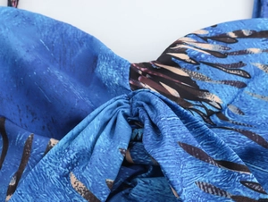 Detailed close-up of blue feather print chiffon fabric with ruched knot design at chest