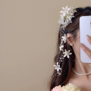 Detail of white fabric floral hair clip with lace and long pearl tassel on model