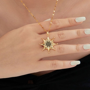 Gros plan du pendentif étoile octogonale dorée avec zircons noirs et blancs