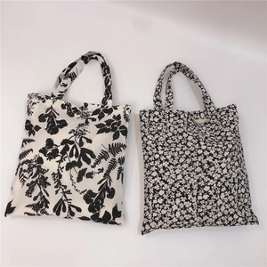 Flat lay of cotton tote bags featuring black leaf patterns and small white floral prints