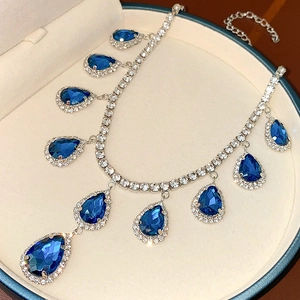 Macro view of blue teardrop gemstones and silver diamond necklace in a jewelry box