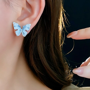 Gros plan de boucles d'oreilles papillon avec ailes bleu clair et détails en zircon