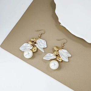 Close-up of pearl earrings with white resin petals and gold heart accents