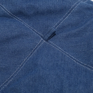 Detailed macro view of the blue denim beret showing white stitching and top fabric loop