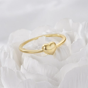 Close-up of golden S925 sterling silver heart ring resting on delicate white flower petals