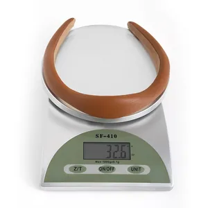 Brown padded PU leather headband weighing 32.6 grams on a digital scale for light comfort