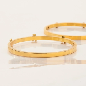 Dettaglio di due bracciali rigidi in acciaio placcato oro 18K con piccoli orsetti