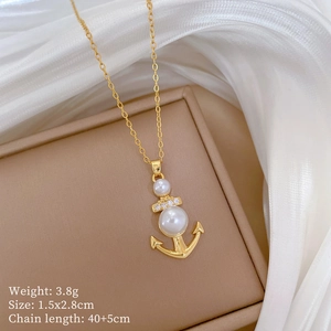 Dettaglio di una collana con ciondolo ad ancora dorata con perle e piccoli cristalli