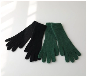 Detailed knit texture of soft green and black winter thermal gloves on white background