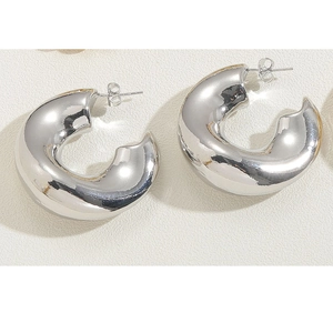 Macro view of chunky silver C-shaped hoop earrings with polished mirror finish