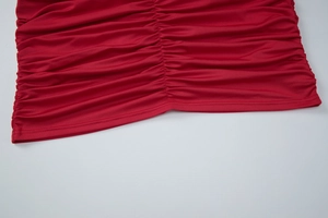 Gros plan détaillé sur le tissu froncé rouge et les coutures fines d'une robe chic