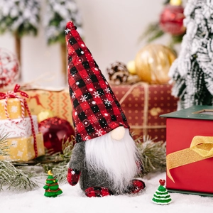 Christmas gnome doll with red plaid snowflake hat sitting in a festive holiday scene