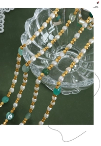 Detailed close-up of beaded necklace with freshwater pearls and green gemstones