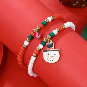 Detail shot of Christmas beaded bracelets with snowman and bell charms on red background